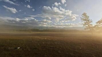 View from the side window of a car. Mountain scenery at sunset with snow-capped peaks in the background. Shot with an action camera. video