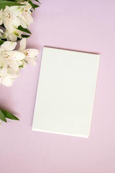 Blank white notepad on pink background with white flowers photo