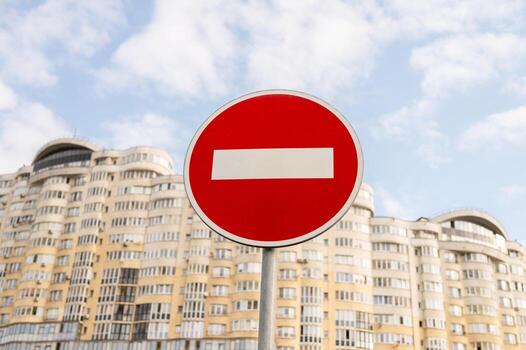 No entry sign against modern apartment building with cloudy sky background photo