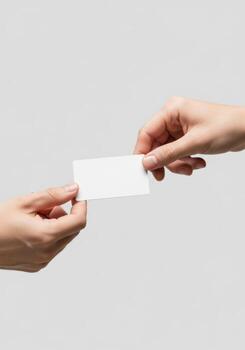 A close-up view of two hands exchanging a blank white business card, a symbol of professional networking and introduction photo