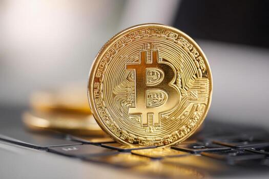 Conceptual image of digital currency featuring a golden coin with blockchain symbol placed on a modern laptop keyboard highlighting cryptocurrency technology and finance photo