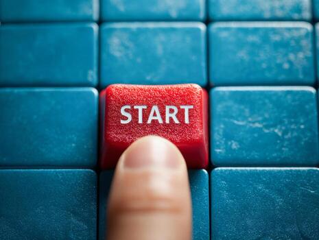 A finger pressing a red start button surrounded by blue keyboard keys symbolizing initiation or beginning of a process or action in business or technology concepts photo