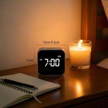 digital alarma reloj mostrando 7 7 00 a.m siguiente a un iluminado vela en un cabecera mesa con un cuaderno y bolígrafo foto