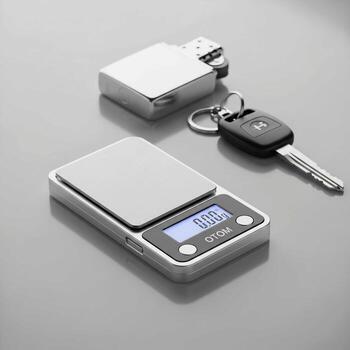 Compact digital pocket scale and car key on a reflective surface showcasing portability and precision for small measurements photo