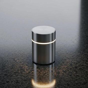 Sleek modern cylindrical container with a subtle illuminated band reflecting on a dark textured surface photo