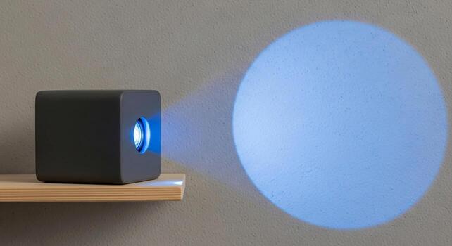 Compact portable mini projector casting a bright blue light beam onto a textured wall surface photo