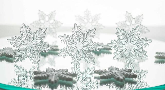 Sparkling white and silver snowflake decorations reflecting on a mirrored surface with a hint of teal photo