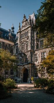 Grand stone building, shaded by trees, in a courtyard photo