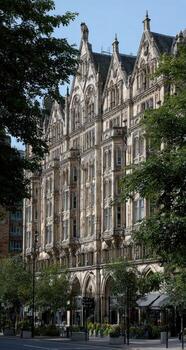 Historic building facade, gothic architecture, tall structure, amongst trees and foliage photo