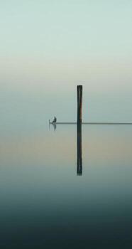 Calm water reflects a single post photo