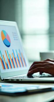 Close-up laptop screen displaying charts and graphs, hands on keyboard photo