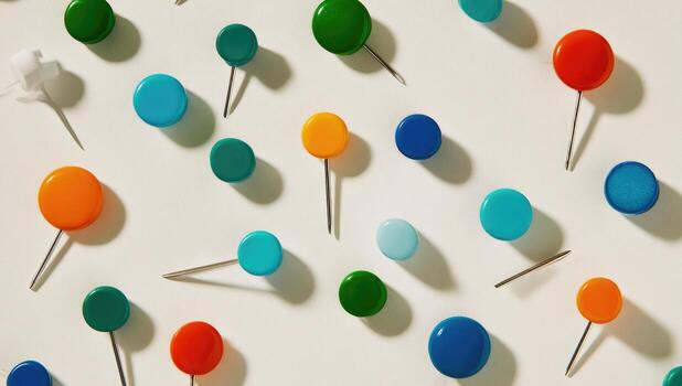 Colorful pushpins scattered on a white surface photo