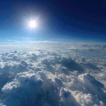High-altitude view of a vast, bright sky, dotted with fluffy white clouds. Sunlight blazes through photo