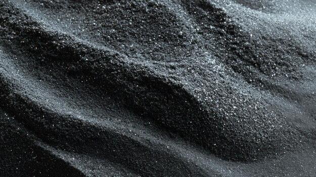 Dark, fine, granular material with soft, textured ripples and light highlights photo