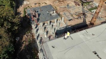 Aerial view of engineers inspecting construction site progress. Two engineers wearing safety vests inspect construction progress from above on a large concrete video