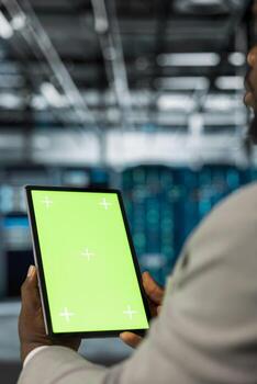 Server farm computer scientist using mockup tablet to repair equipment storing datasets. IT expert using green screen device to do debugging on mainframes doing computational operations photo