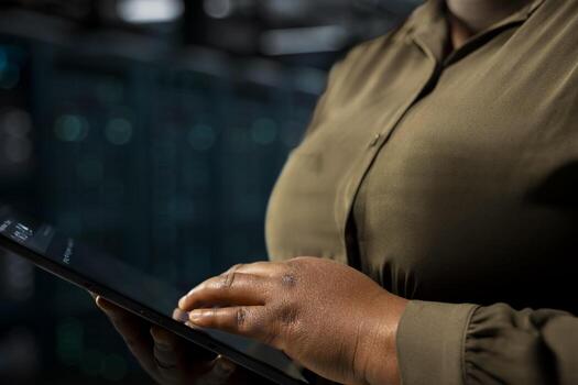 Close up of data center engineer using tablet to optimize network infrastructure, planning capacity. IT specialist managing server farm resources with device for improved reliability and uptime photo