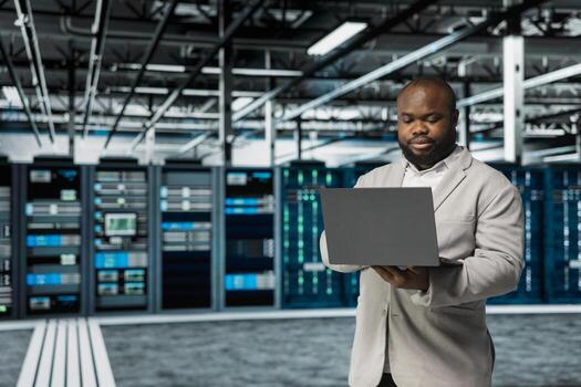 Data center software developer running error checking utilities on laptop, automating anomaly detection. Server hub IT professional monitoring hardware performance, looking for network issues photo