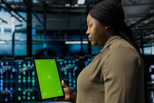 Manager uses isolated screen tablet to do checkup on data center electronics datasets. Server hub supervisor does backups on mockup device to protect gear used by cloud storage hosting companies photo