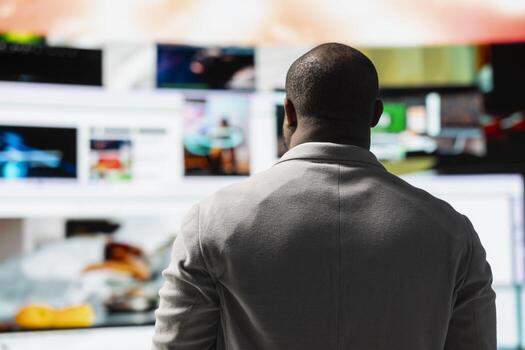 Man looks at immersive videowall, celebrating freedom of unlimited content libraries. Viewer in virtual space filled with broadcasting channels, social media feeds and multimedia clips photo