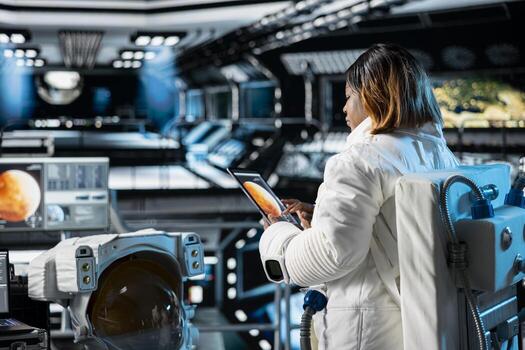 Female astronaut in orbital station analyzing Mars planetary data on tablet. Crew member in spaceship doing Martian surface research using device to assist future planetary exploration photo