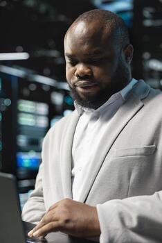 Close up of data center programmer using laptop to protect servers from exploitable software vulnerabilities, auditing systems. Server hub worker looking for bugs slowing down equipment photo