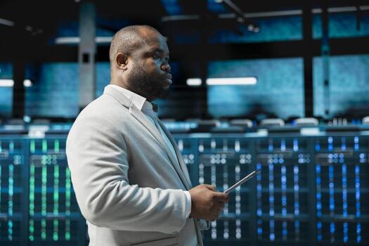 Data center admin monitoring thermal levels using tablet, doing checkup to prolong hardware life span. Server hub worker monitoring infrastructure rigs, reviewing configurations photo