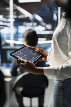 Close up of engineer using tablet, coding in data center, updating neural networks scripts. Worker in server hub programming machine learning algorithms, debugging equipment mainframes photo