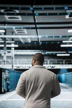 Computer scientist walking in server farm, overseeing mainframes gear used for managing databases. IT specialist in high tech data center doing checkup on rackmounts storing information photo