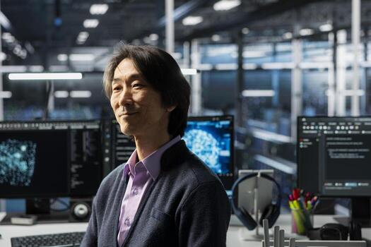 Smiling senior programmer in data center working on databases supporting AI applications. Happy Asian IT expert in server hub conducting experiments on artificial intelligence algorithms improvements photo