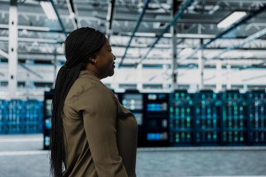 Technician walking through server room rows lined with storage infrastructure rigs. IT professional inspecting high tech data center helping power internet services for enterprise customers photo