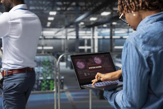 Stressed panicked woman handling cybercriminal threat response, trying to save data center sever rigs during security breach. Worried engineer reads a critical error alert on laptop. photo