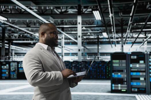 Data center engineer using laptop to automate errors detection, minimizing downtime. Server hub IT expert monitoring components for potential failures, looking for network issues affecting rigs photo