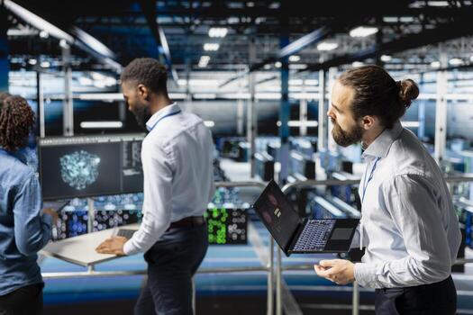 Worried technician in server room detecting hacking attempt targeting data systems and panicking about data breach. Engineering team under pressure by virus activity, emergency protocol. photo