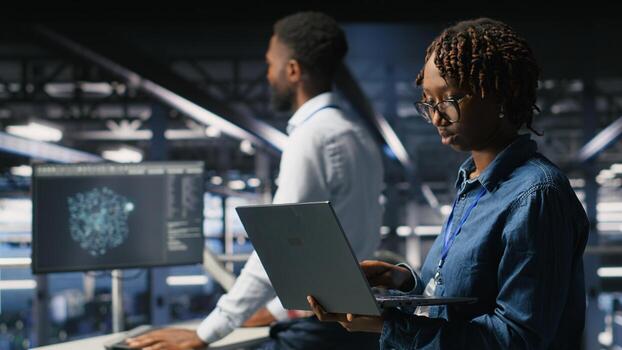 Data scientist in server farm reviewing neural network code and LLM visualization dashboards. IT expert walking on data center industrial platform, monitoring AI system performance photo