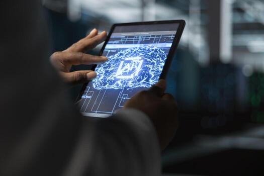 Close up of data center programmer using artificial intelligence computerized model on tablet to oversee equipment. Server hub worker working with AI machine learning algorithms on device photo