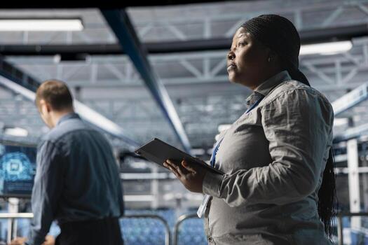 Server room infrastructure engineers scripting automated workflows using software on tablet. Teamworking data center programmers running predictive maintenance scans using device photo