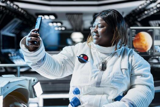 Happy astronaut doing videocall with family before landing spaceship on Mars. Woman using smartphone, talking with loved ones during mission to red planet surface to test human survival in deep space photo