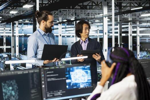 Multiethnic coworkers coding in diverse data center, updating AI automation scripts. Multiracial server room colleagues doing brainstorming, programming artificial intelligence algorithms photo