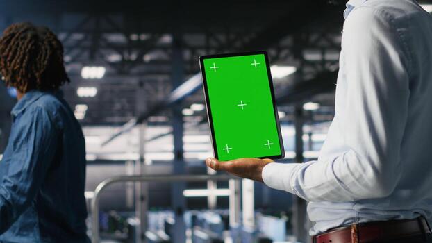 Close up of server hub admin using isolated screen tablet next to colleague reviewing AI LLM visualization. Data center employee using mockup device to monitor machine learning systems photo
