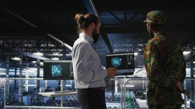Military operator and IT expert in army data center using AI on laptop to manage autonomous defense systems. Soldier and programmer using AI for strategic threat detection, photo