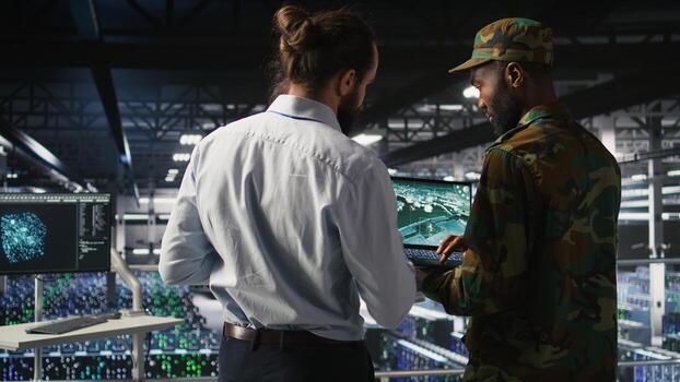 Army operators in data center using laptop to run drone control software, looking at mission map overlay. Military experts doing strategic deployment of autonomous aerial vehicles photo