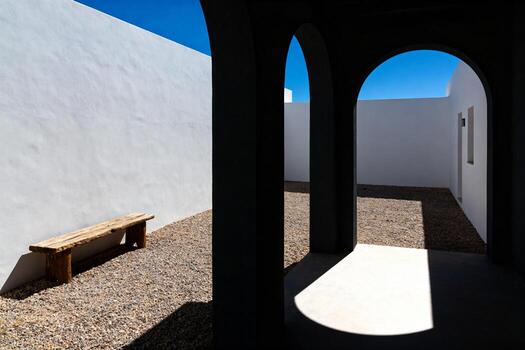 A bench sitting in a courtyard with a wall behind it photo