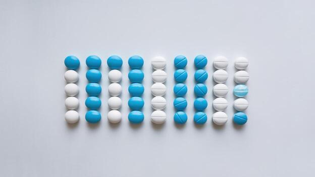 Blue and White Pills Arranged in Rows on a White Surface photo