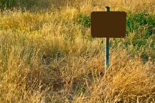 Rusty red frame for text on an old pipe in a field with dry grass photo