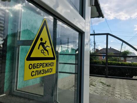 A yellow caution sign on the window of a building photo