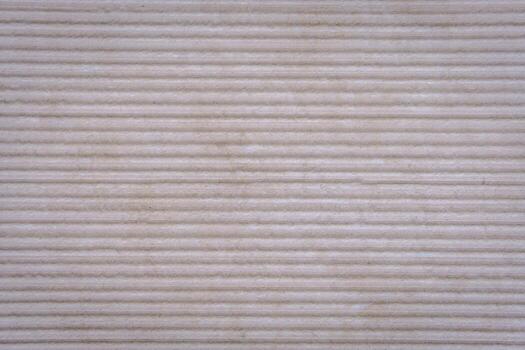 A textured stone surface with evenly spaced horizontal ridges forms a rhythmic pattern. The material emphasizes durability and the natural expressiveness of texture. photo