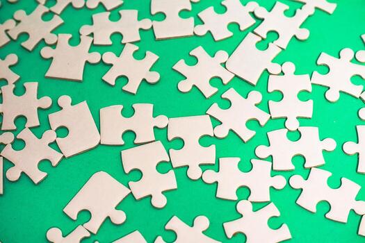 Scattered jigsaw puzzle pieces on a vibrant green background create a chaotic yet intriguing visual photo