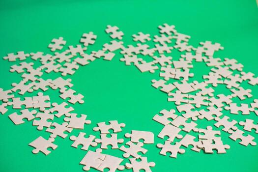 Scattered white jigsaw puzzle pieces on green background, representing incomplete projects and the challenge of finding the solution photo