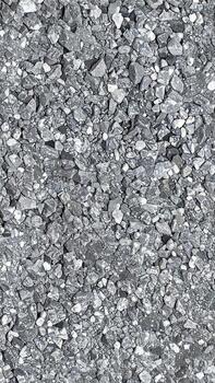 Overhead shot of a tightly packed, textured surface composed of small, irregularly shaped gray stones. Variations in light and shadow create depth, highlighting the jagged edges and facets. photo